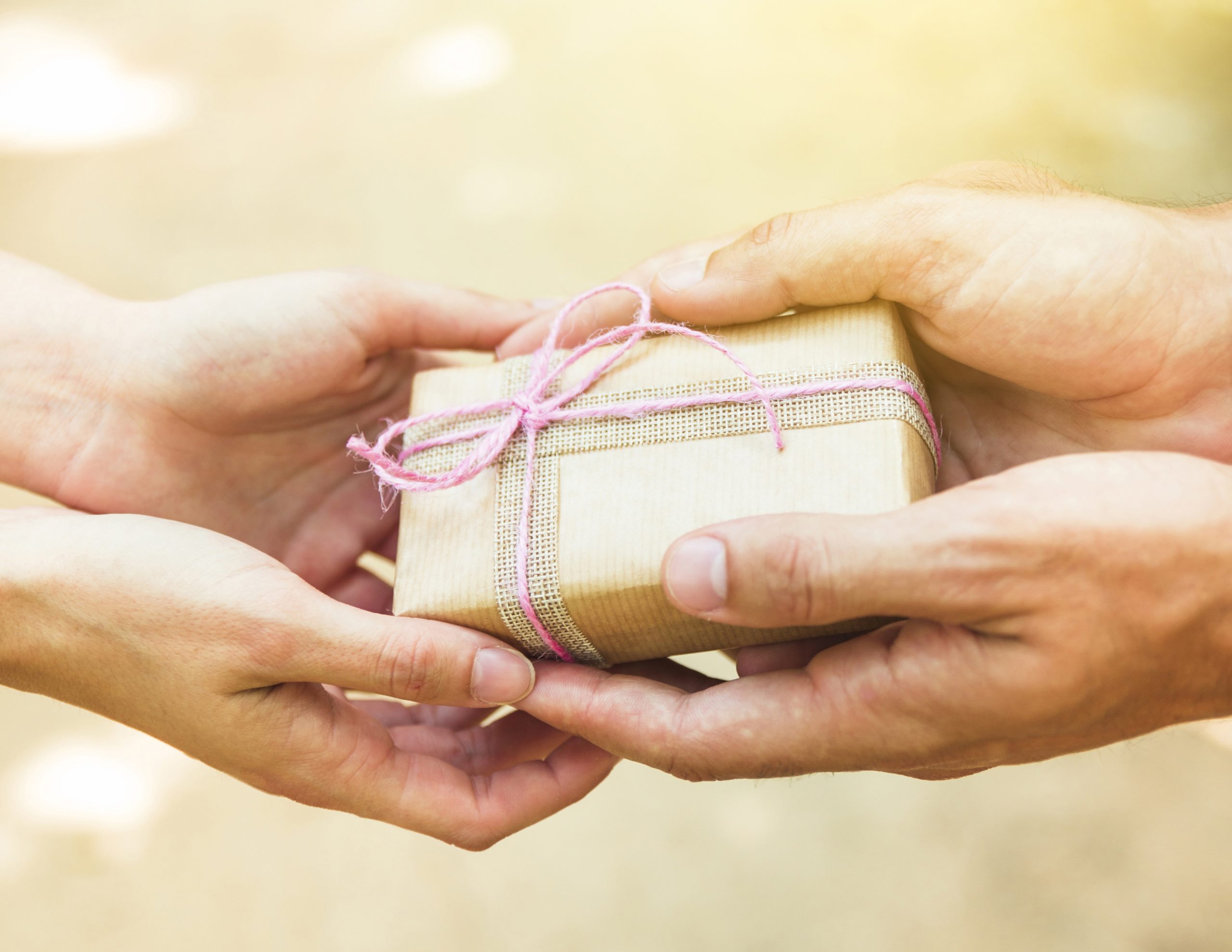 close-up-couple-s-hand-holding-tied-valentine-gift